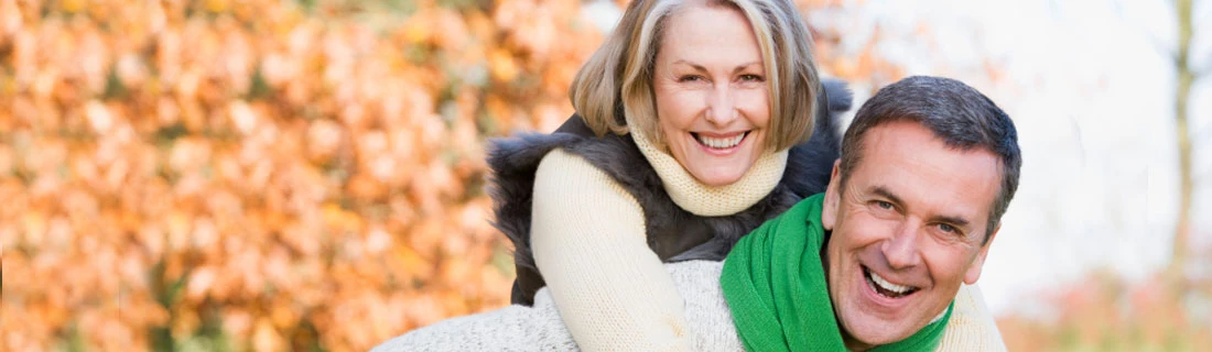 Older Couple Smiling Outside In Fall