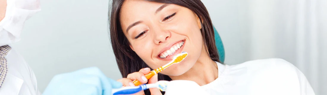 Dentist Showing Woman How To Brush Teeth