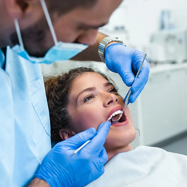 Dentist-Performing-A-Cleaning-On-Woman-600x600-Moto.webp